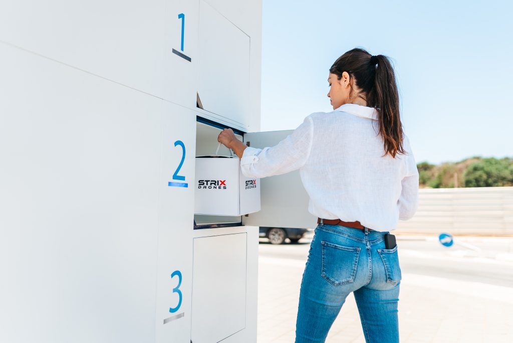 women pick up a package from drone delivery mailbox